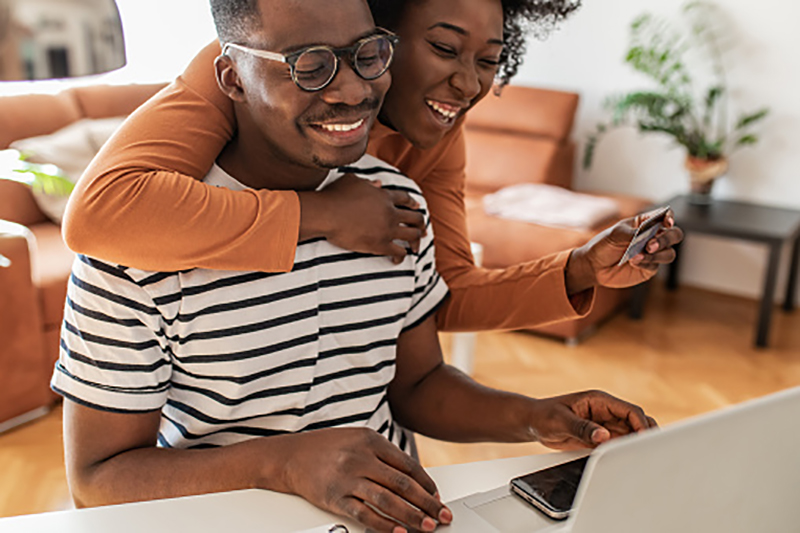 Photo of young couple, smiling and doing online shopping from home