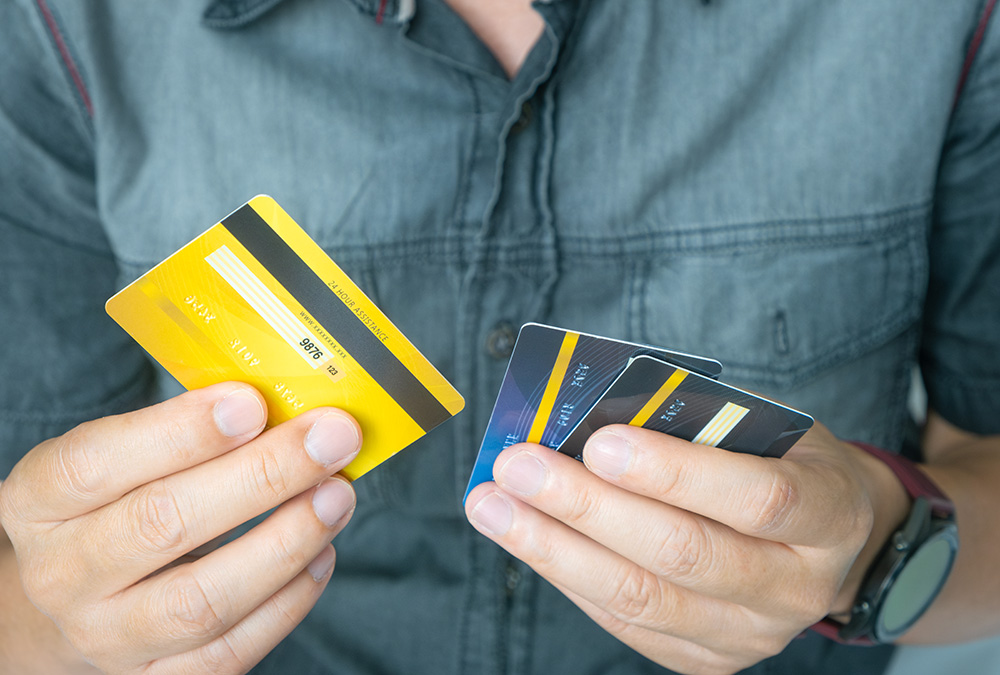 A man holding debit and credit cards in his hand to chose which one to use