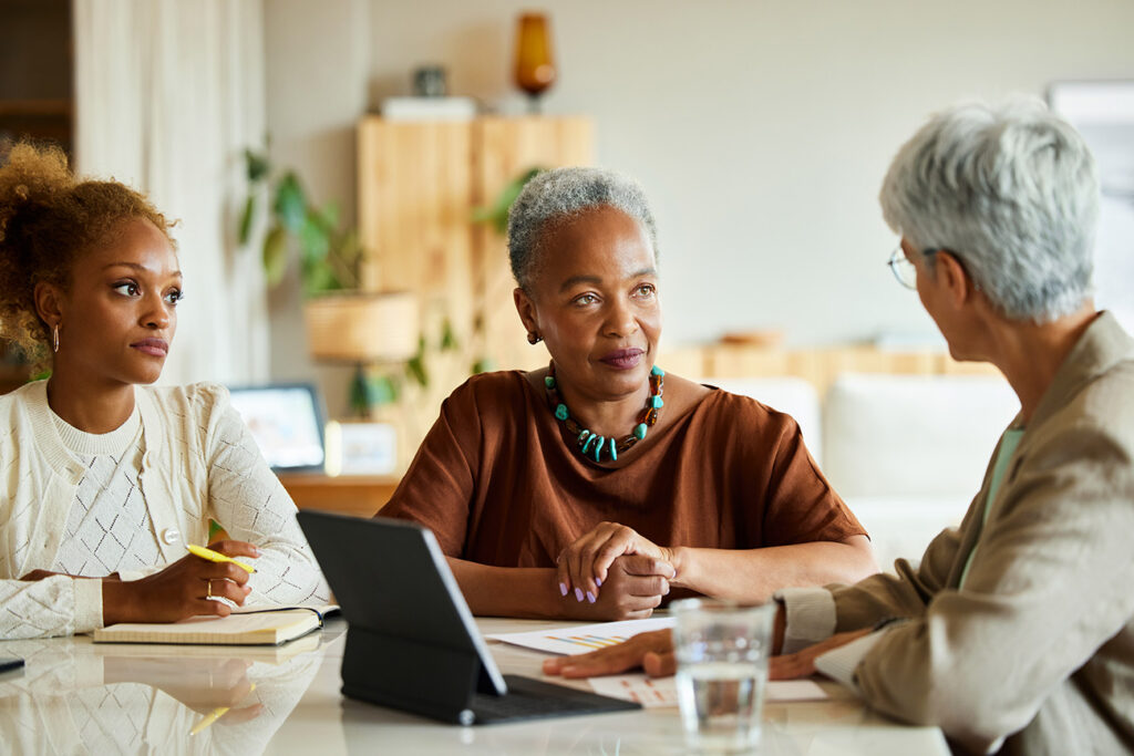 Mature female advisor discussing with family. Senior woman and daughter are listening to finance manager.